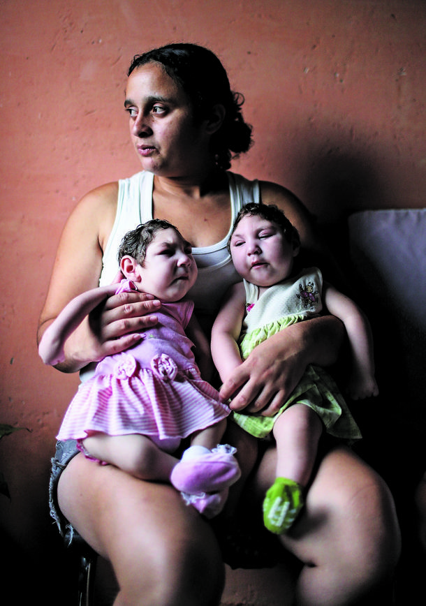 Mother Raquel Bholds her twin daughters Eloa (L) and Eloisa, 8 months old and both born with microcephaly, while posing in the home of grandparents of the twins on December 16, 2016 in Areia, Pernambuco state, Brazil. 