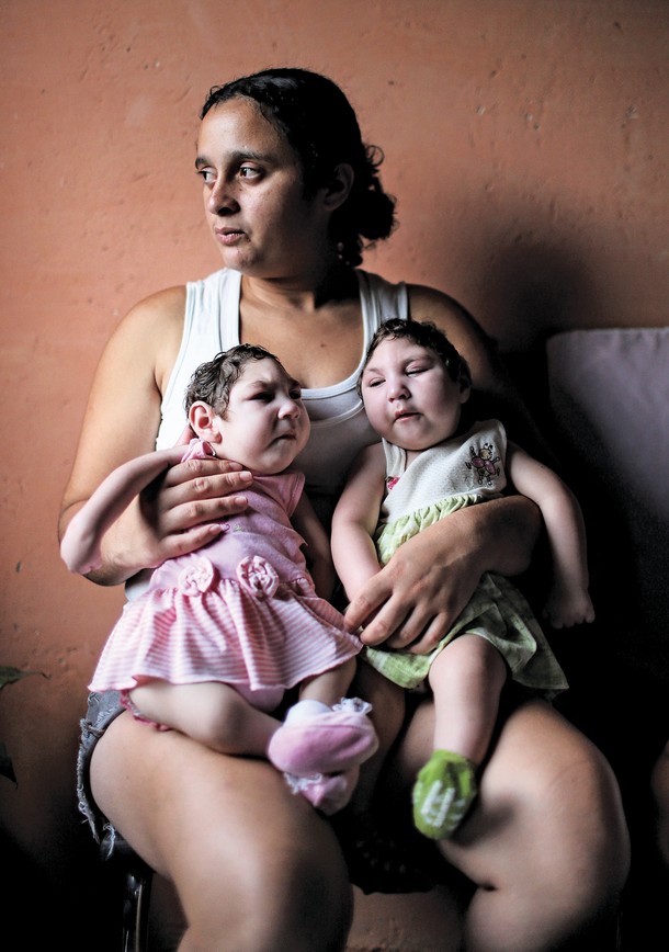 Mother Raquel Bholds her twin daughters Eloa (L) and Eloisa, 8 months old and both born with microcephaly, while posing in the home of grandparents of the twins on December 16, 2016 in Areia, Pernambuco state, Brazil. 