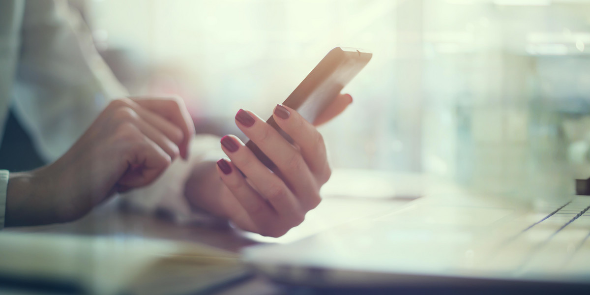 Modern workplace woman using mobile phone in office.