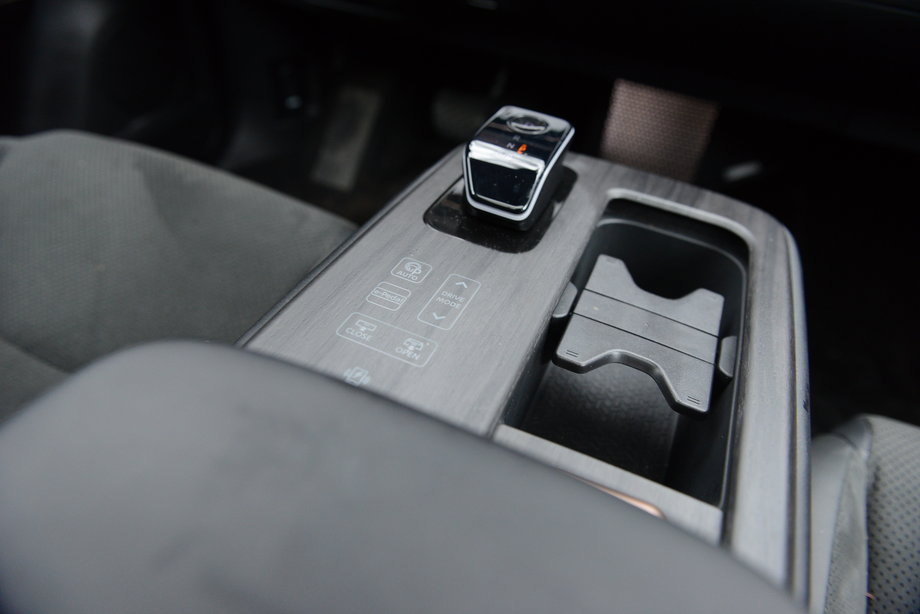 Nissan Ariya - na środkowej konsoli mamy niewielką dźwignię do wyboru jazdy do przodu lub do tyłu, a obok zestaw płaskich, dotykowych przycisków, m.in. do otwierania szyberdachu, ale też do zmiany trybu jazdy.