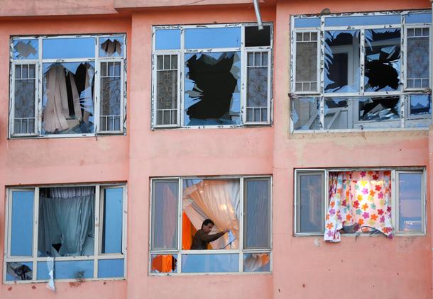 An Afghan man removes glasses from his apartment at the site of a suicide attack in Kabul, Afghanist