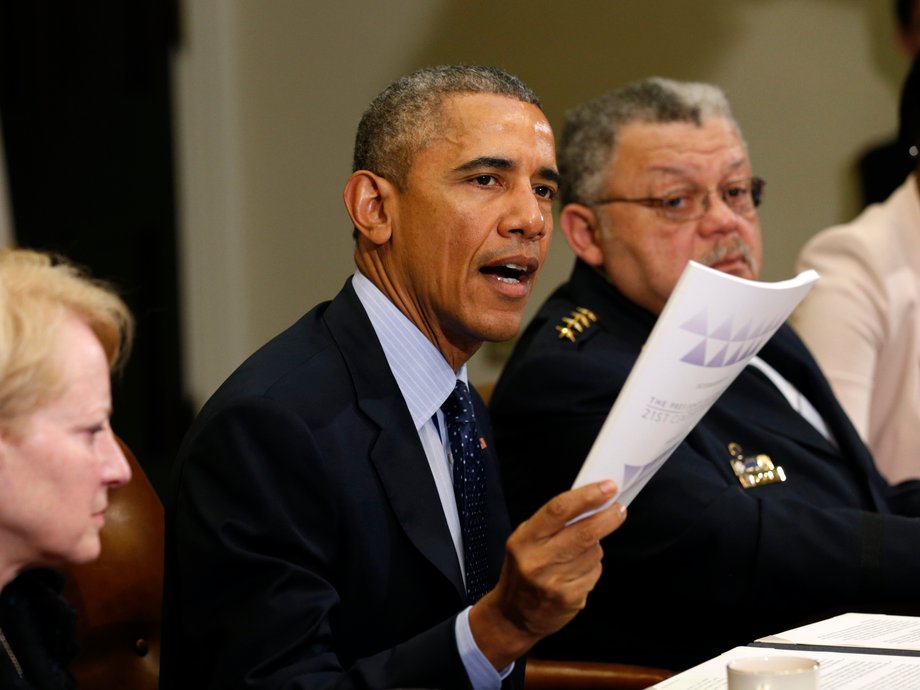 U.S. President Barack Obama holds up a copy of the report by the Task Force on 21st Century Policing at the White House in Washington March 2, 2015. eside Obama at right is Philadelphia Police Commissioner Charles Ramsey.