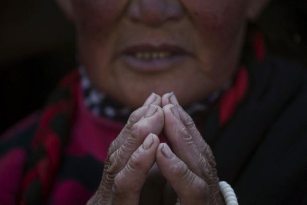 Woman prays as ethnic Tibetan people gather in sub zero temperatures on the hill above a Buddhist la