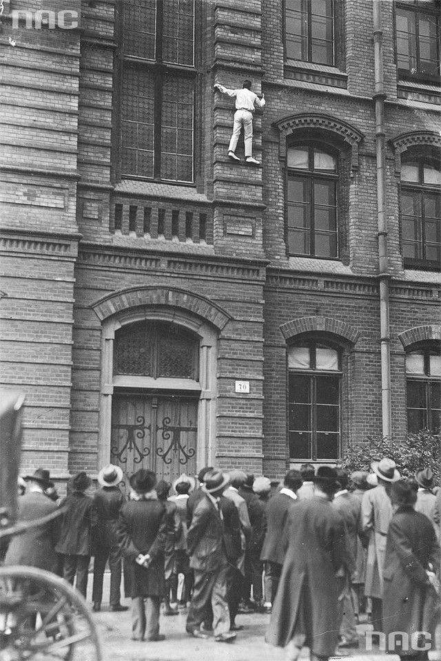 Akrobata Stefan Poliński wspina się na budynek przy ul. Dietla