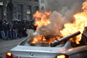 Protesters are seen past a burning car during a rally against Expo 2015 in Milan