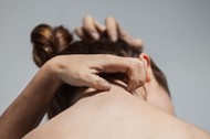 Portrait from behind of woman scratching