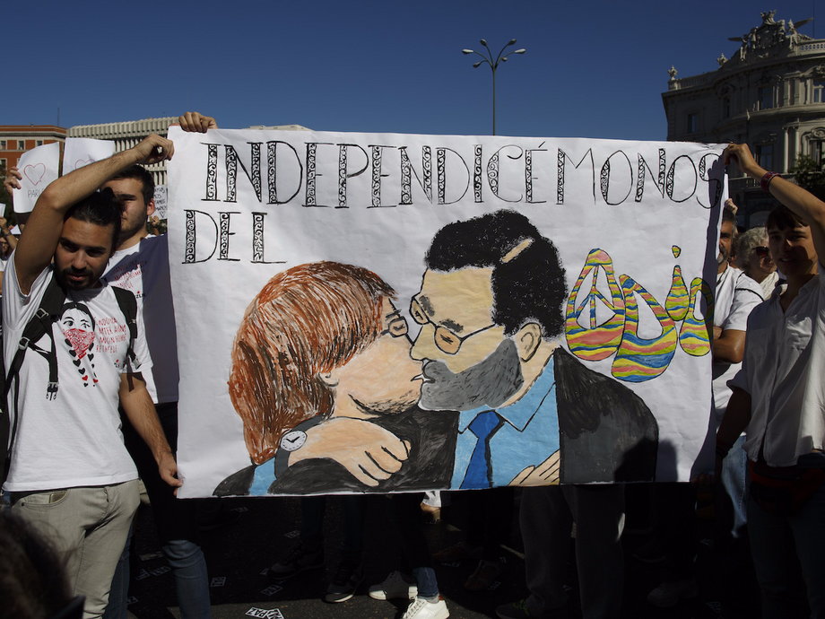 Demonstrators hold up a banner depicting Puigdemont and Spanish Prime Minister Mariano Rajoy kissing, with the caption: "Let's get rid of hate."