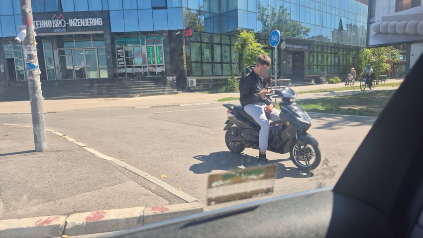 Mladić na električnom skuteru sa slušalicama na ušima