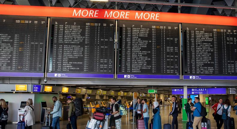 Passengers wait and queue to rebook their flights in front of a schedule board.Andre Pain/AFP via Getty Images