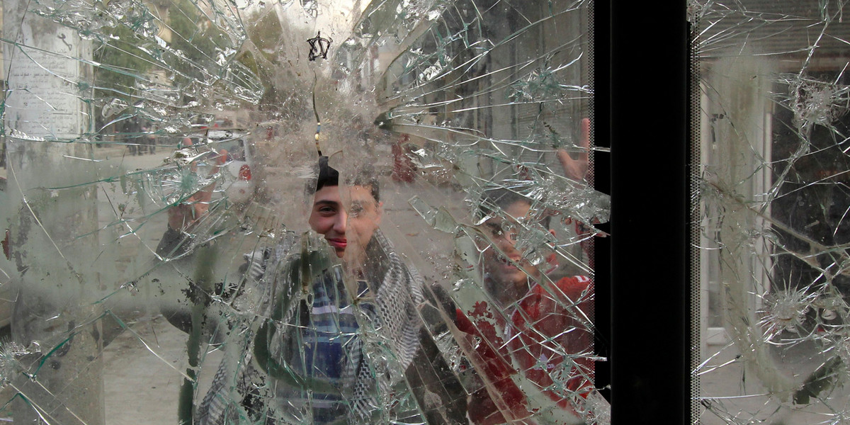 Boys are pictured through a broken windshield as they stand on a street in Aleppo February 28, 2013. R
