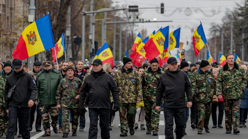 Mężczyźni w strojach wojskowych maszerujący przed protestującymi podczas antyrządowego protestu w Mołdawii, 13 listopada 2022 r.