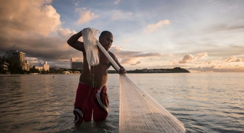 A fisherman works off a beach at Tumon Bay in Guam