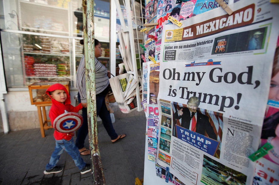 A woman and her son walk past a newspaper stand displaying a local newspaper with a headline about the victory of US Republican president-elect Donald Trump, in Ciudad Juarez, Mexico.