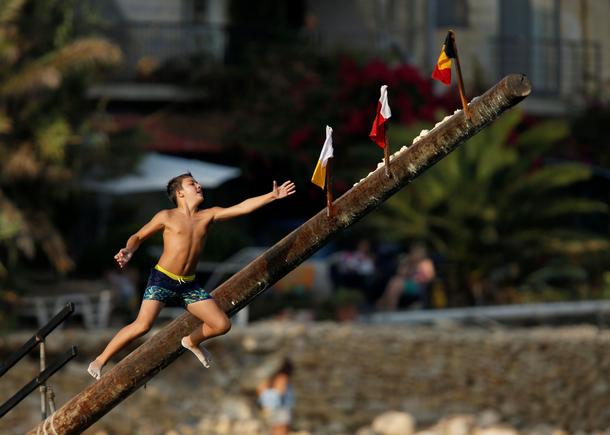 A child tries to grab a flag on the gostra, a pole covered in grease, during the religious feast o