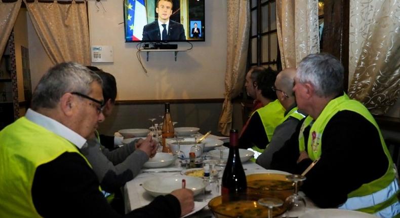 'Yellow vest' protestors take notes as they watch French President Emmanuel Macron's speech on television