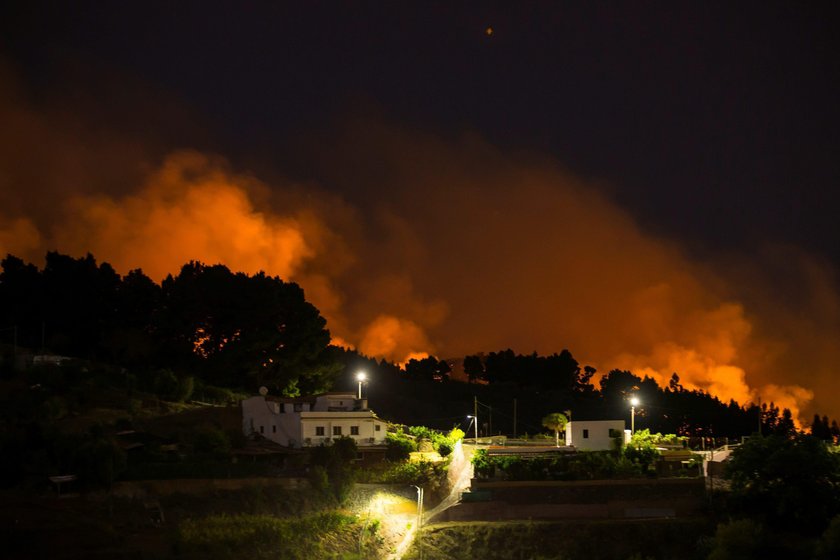 Flames and smoke from a forest fire are seen in the village of Valleseco