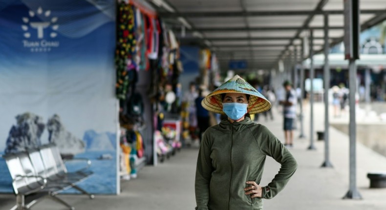 A woman wearing a face mask walks along the Tuan Chau harbour in Ha Long Bay, Vietnam