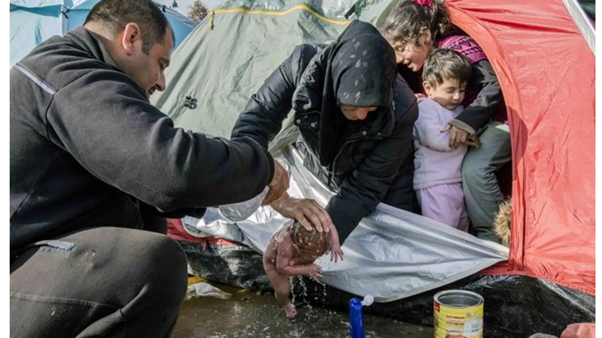 Wzruszające zdjęcie z obozu imigrantów. Dziecko myte w kałuży