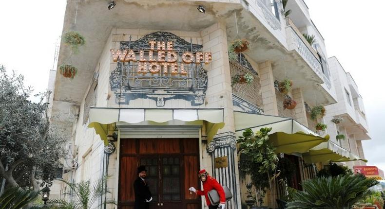 A bellboy stands outside UK street artist Banksy's newly-opened Walled Off hotel in the West Bank town of Bethlehem, on March 3, 2017