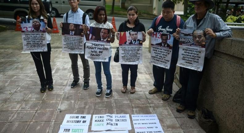 Relatives of passengers missing on Malaysia Airlines MH370 hold placards after a joint press conference of the Ministerial Tripartite Meeting on the search for the missing flight outside Kuala Lumpur on July 22, 2016