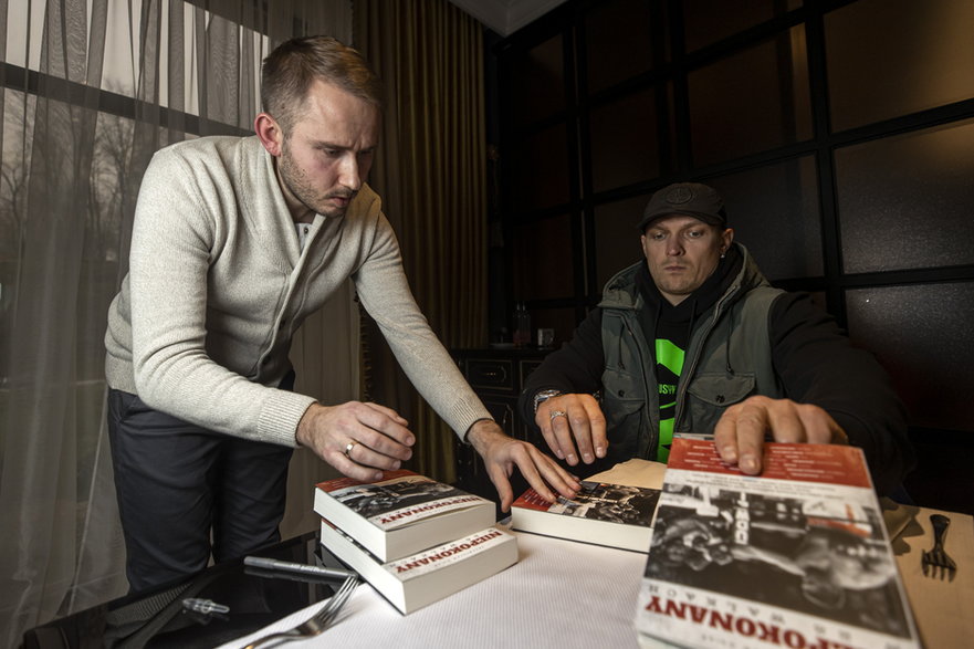 Ołeksandr Usyk podpisuje książkę "Niepokonany w 28 walkach", która trafiła na licytację na rzecz Ukrainy