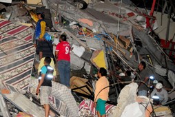 People stand on the debris of a building after an earthquake struck off the Pacific coast in Manta