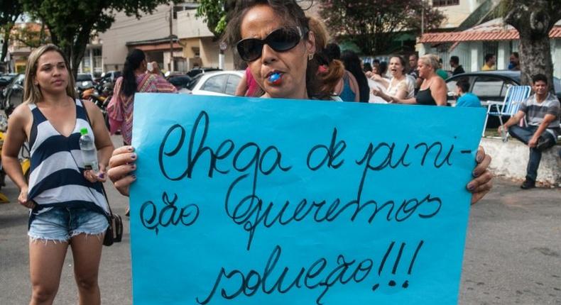 A relative of a military police shows a sign reading Enough of punishment, we want solutions! during a protest in support of a police strike at the entrance of a police station in Vila Velha, near Vitoria, in eastern Brazil on February 6, 2017