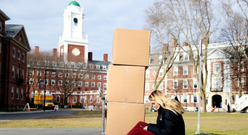 A Harvard student sits with her belongings before returning home on March 12, 2020, as students left campus due to the coronavirus pandemic