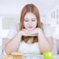 Confused woman choose apple or hamburger