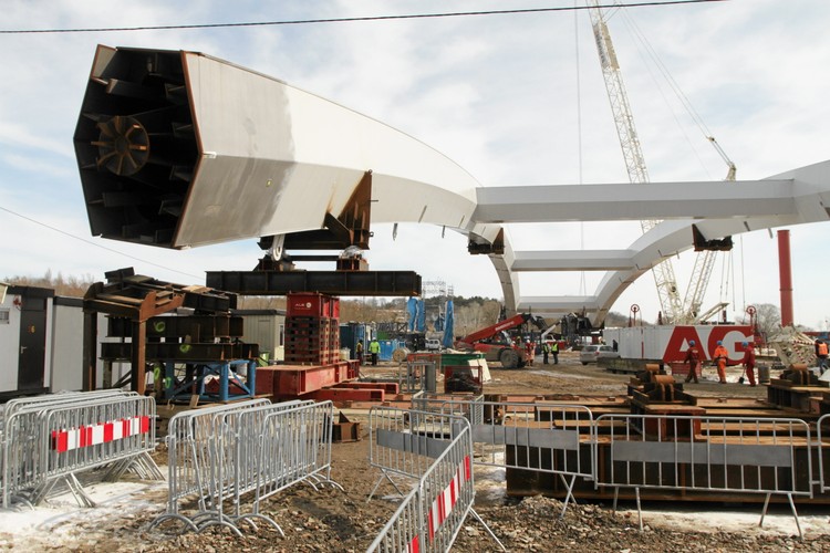 Jak czytamy na oficjalnej stronie internetowej inwestycji, projekt zakłada zwodowanie specjalnymi pontonami gotowych łuków mostu o łącznej masie ok. 5,5 tys. ton na miejsce docelowe na podpory stałe mostu. Jeszcze nigdy w Polsce nie przeprowadzano montażu elementów o tak dużych gabarytach i tak wielkim tonażu.