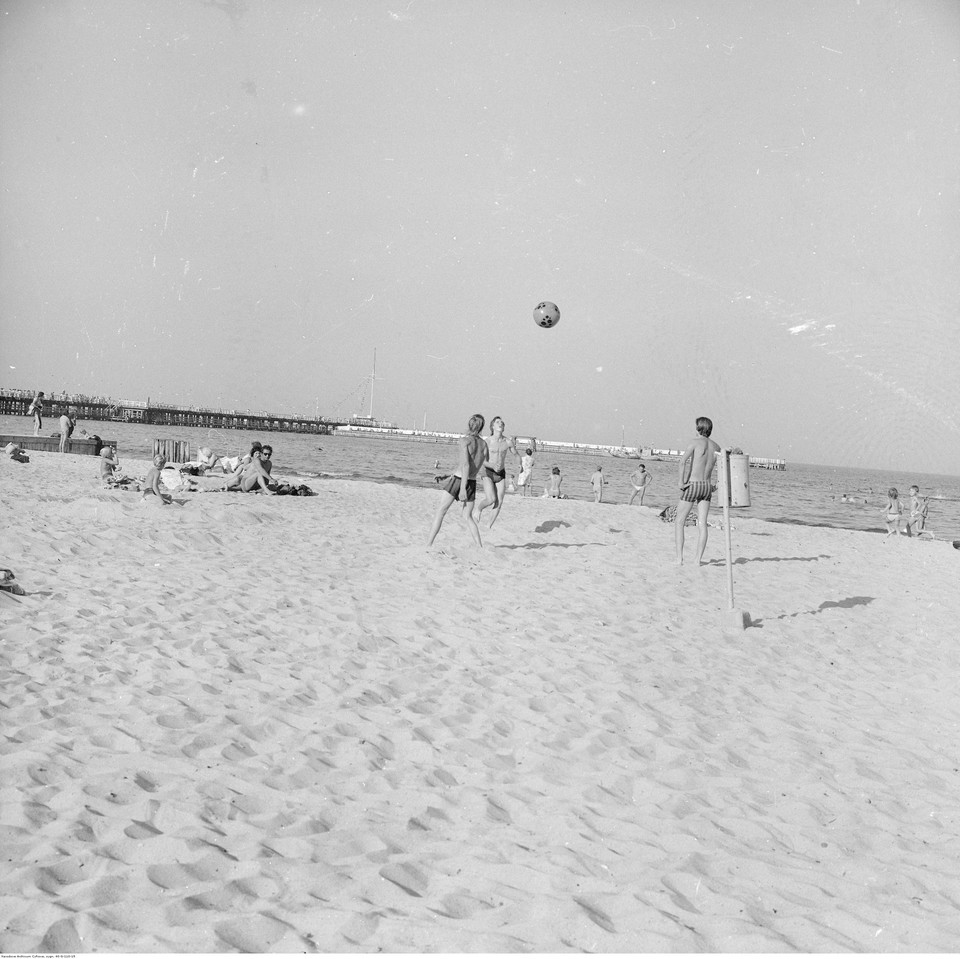 Gra w siatkówkę na plaży. W oddali molo