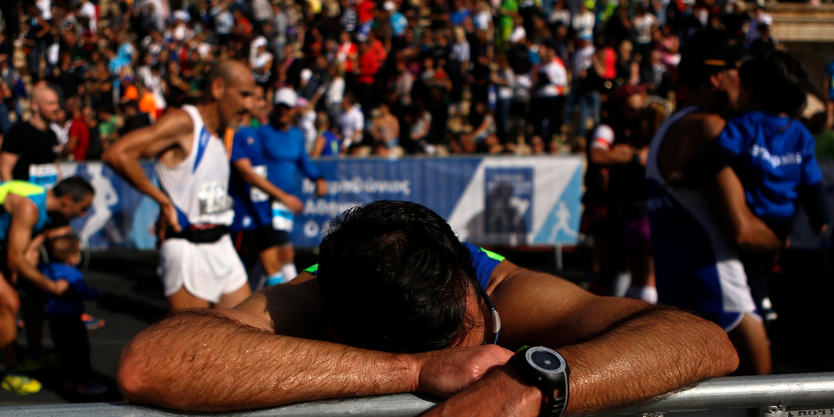 An athlete catches his breath after crossing the finish line during the 32nd Athens Classic Marathon at the Panathenaic Stadium in Athens on November 9, 2014.