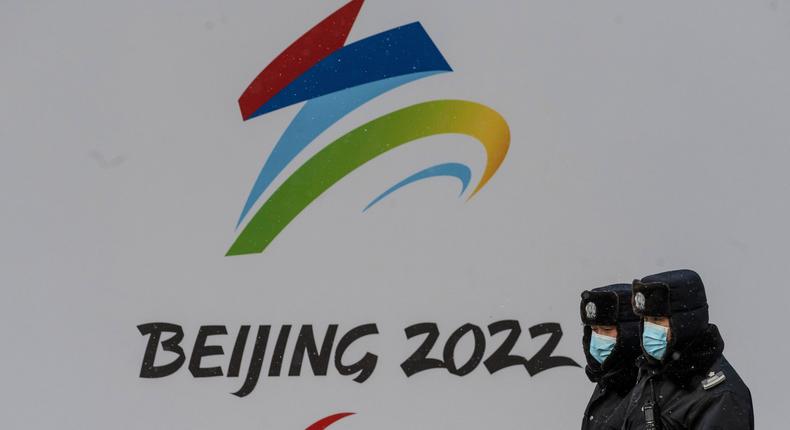 Security walk by a billboard for the Beijing 2022 Winter Olympics and Paralympics during a snowfall on January 20, 2022 in Beijing, China.