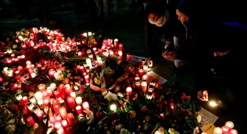 People light candles at a makeshift memorial in front of the Kaiser-Wilhelm-Gedaechtniskirche in Berlin, where a truck crashed the day before into a Christmas market