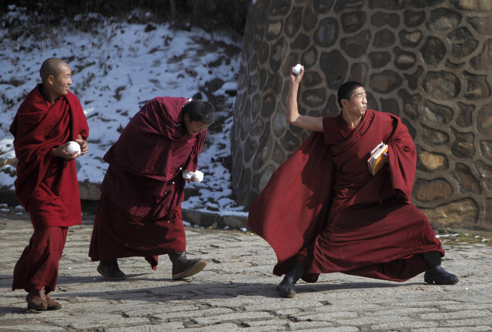 Tibetan monks play with snow at the Taer Monastry in Huangzhong county