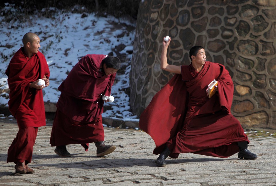 Tibetan monks play with snow at the Taer Monastry in Huangzhong county