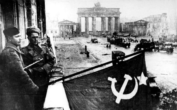 Berlin 1945. Sowieccy żołnierze z flagą ZSRR w zdobytej stolicy III Rzeszy (fot. Bundesarchiv Bild 183-R77767, Berlin, Rotarmisten Unter den Linden” autorstwa Bundesarchiv, Bild 183-R77767 / CC-BY-SA)