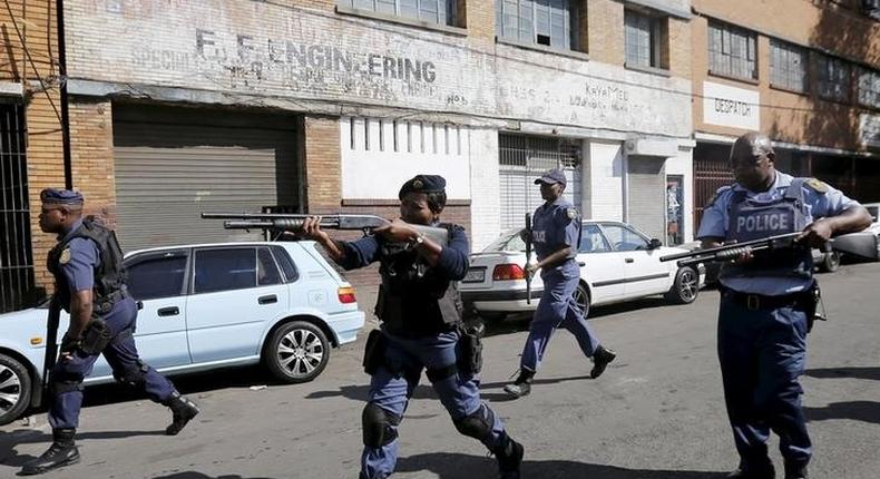 Police officers fire rubber bullets as they disperse African immigrants who are carrying machetes in Johannesburg, April 17, 2015 REUTERS/Siphiwe Sibeko