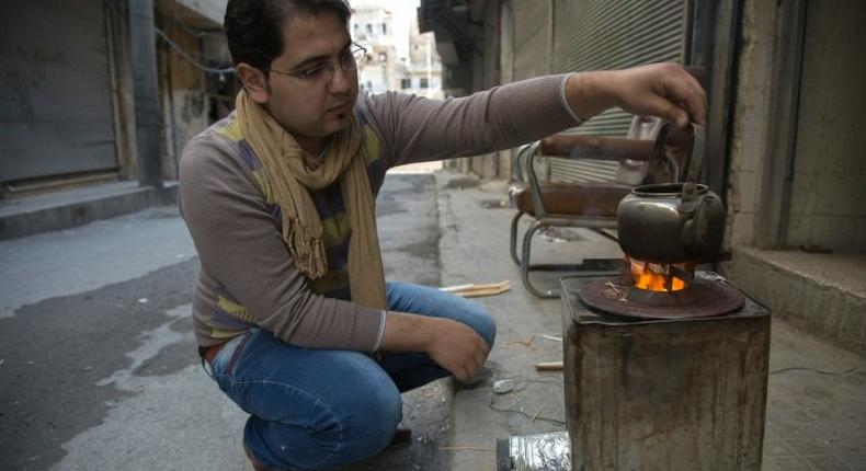 Khaled Kurdiyah, who runs an internet cafe, uses a metal container outfitted with a fan to create a highly-controlled fire to replace rare gas-fired stoves while using minimal firewood, in besieged Aleppo
