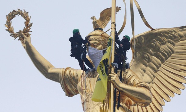 Greenpeace activists climb the Golden Victoria monument on top of the Victory Column and install a b