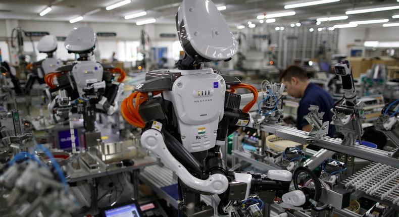 Humanoid robots work side by side with employees in the assembly line at a factory of Glory Ltd., a manufacturer of automatic change dispensers, in Kazo, north of Tokyo, Japan, July 1, 2015.