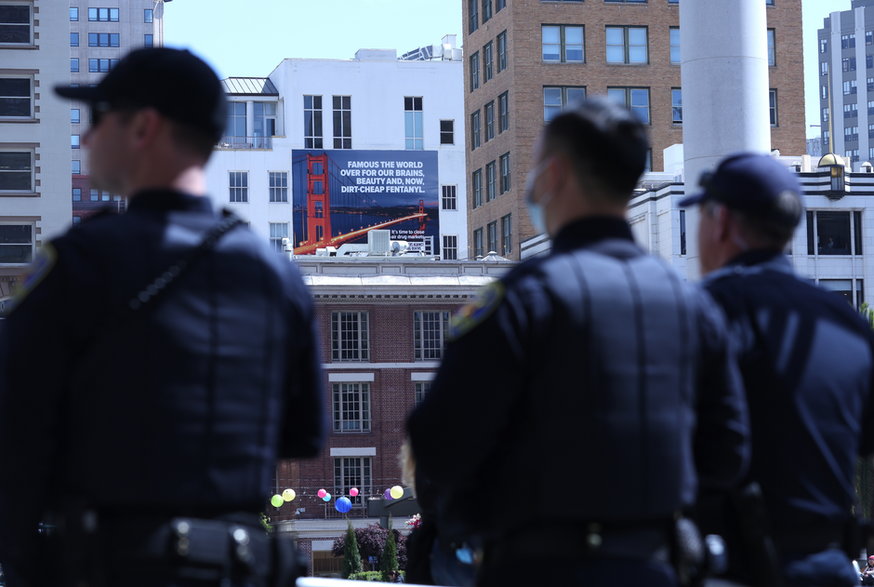 Policjanci w San Francisco patrzą na bilboard z panoramą miasta i napisem: "znane na całym świecie ze zdolności, piękna i taniego fentanylu"