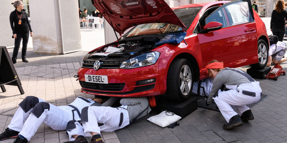 Członkowie Greenpeace, w ramach akcji protestacyjnej, demontują samochód VW przed budynkiem, w którym odbywa się wystawa wspierana przez Volkswagena, maj 2018 r. 