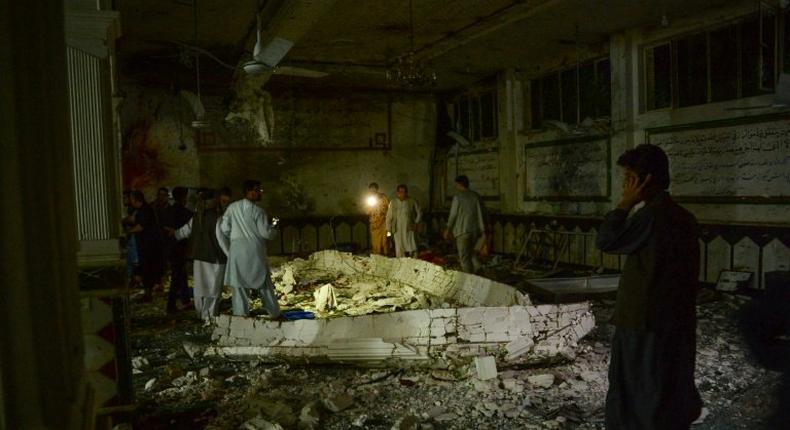 Afghan security personel inspect the site of a suicide bomb attack at a Shiite mosque in Herat on August 1, 2017
