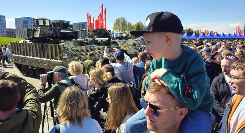 A boy sitting on the shoulders of a visitor observes several vehicles, including the Bradley IFV.Contributor/Getty Images