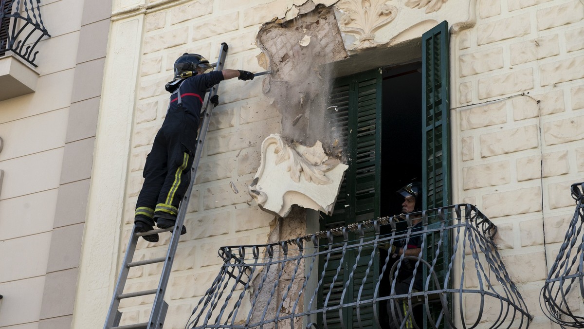 Firemen remove a part of a damaged facade of a building in Melilla