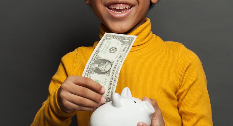 Stock image of a boy with a dollar bill.JNemchinova | Getty Images