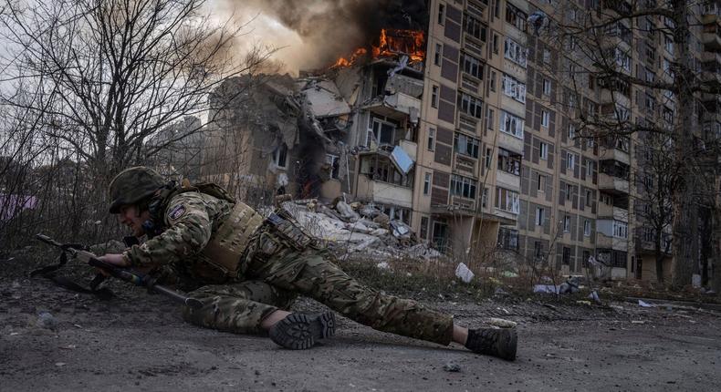 A Ukrainian police officer takes cover in front of a burning building in Avdiivka, Ukraine, March 17, 2023.AP Photo/Evgeniy Maloletka