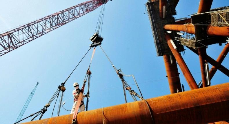 A worker stands on pipes at an offshore oil engineering company in Qingdao, in China's eastern Shandong province