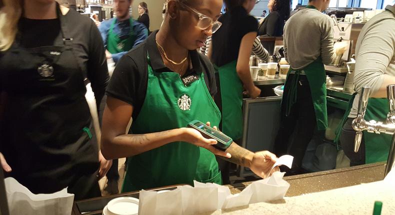 A barista scans a receipt to send a customer a text message saying their order is ready.